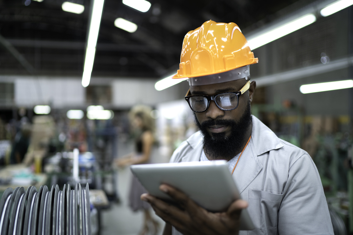 Welder examining tablet on shop floor